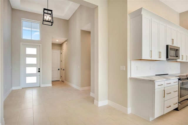 kitchen featuring white cabinetry, decorative backsplash, baseboards, and appliances with stainless steel finishes