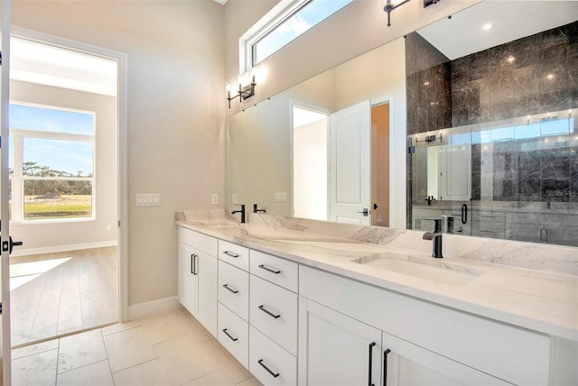 bathroom with double vanity, baseboards, a stall shower, and a sink