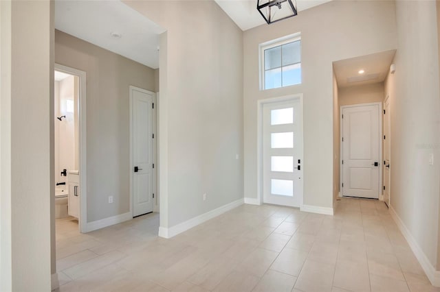 entrance foyer with baseboards and a towering ceiling