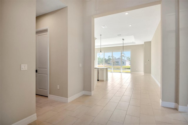 empty room featuring recessed lighting, a tray ceiling, and baseboards