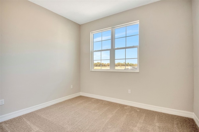 spare room featuring baseboards and light carpet