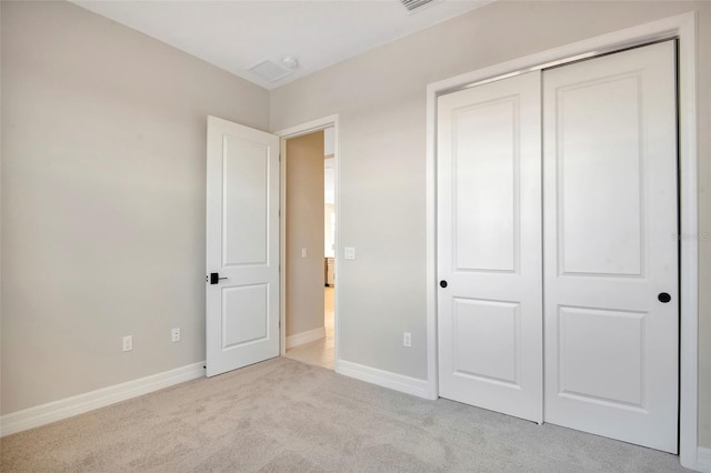 unfurnished bedroom with a closet, light carpet, baseboards, and visible vents