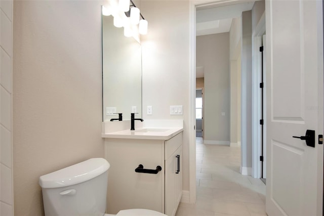 half bathroom with vanity, tile patterned floors, toilet, and baseboards