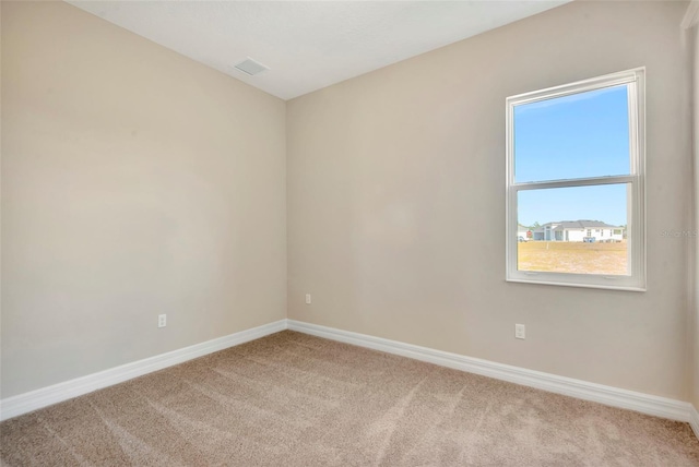 carpeted spare room with visible vents and baseboards