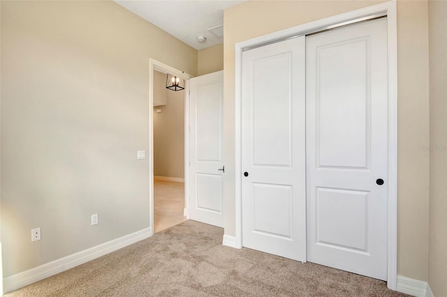 unfurnished bedroom with a closet, baseboards, and carpet