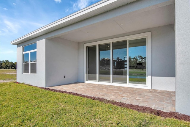 back of house featuring a patio area, a lawn, and stucco siding