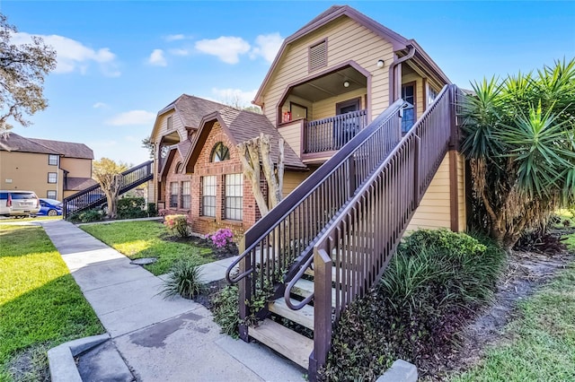 view of front of home with a front yard, stairway, and brick siding