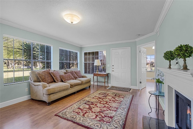 living area featuring a textured ceiling, a healthy amount of sunlight, wood finished floors, and crown molding