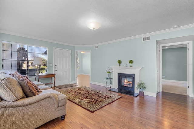 living area featuring visible vents, a textured ceiling, wood finished floors, and crown molding