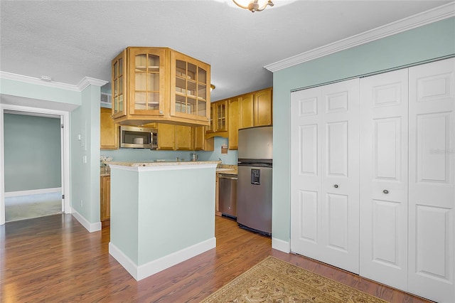 kitchen featuring ornamental molding, dark wood-style floors, appliances with stainless steel finishes, light countertops, and glass insert cabinets