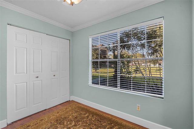 unfurnished bedroom featuring wood finished floors, baseboards, a closet, crown molding, and multiple windows