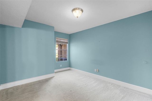 spare room featuring baseboards, carpet, and a textured ceiling