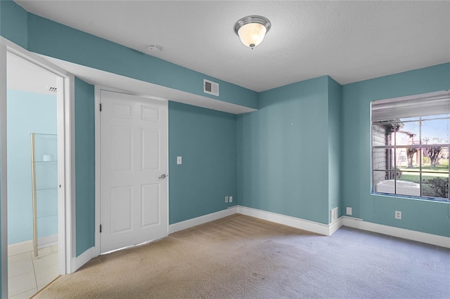 spare room with visible vents, baseboards, carpet floors, and a textured ceiling