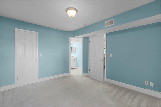 spare room featuring visible vents, a textured ceiling, baseboards, and carpet floors