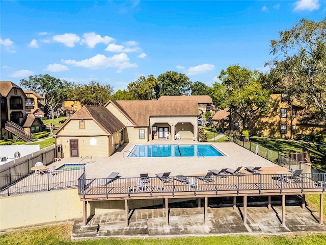 pool featuring a patio, a deck, and fence