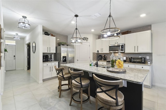 kitchen with visible vents, a sink, backsplash, stainless steel appliances, and a toaster