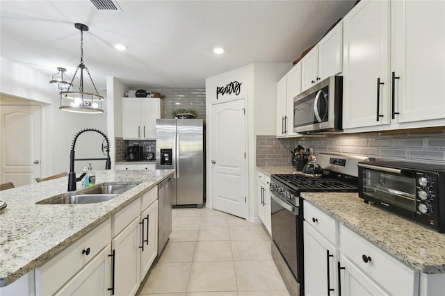 kitchen with light tile patterned floors, decorative backsplash, stainless steel appliances, white cabinetry, and a sink