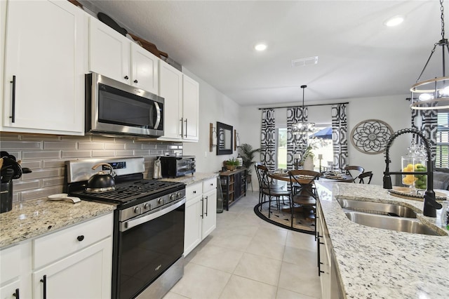 kitchen with visible vents, backsplash, stainless steel appliances, white cabinetry, and a sink