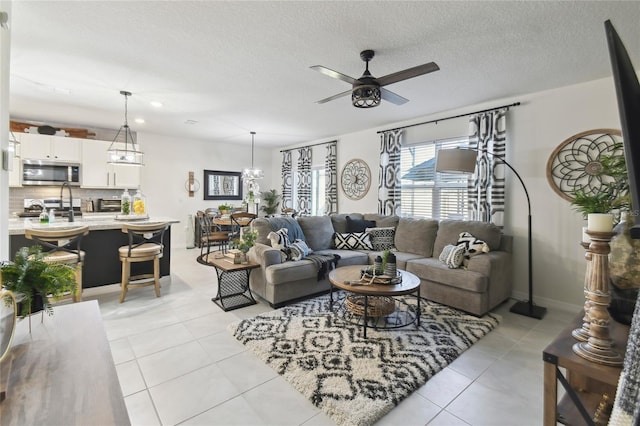 living area with light tile patterned floors, ceiling fan with notable chandelier, and a textured ceiling