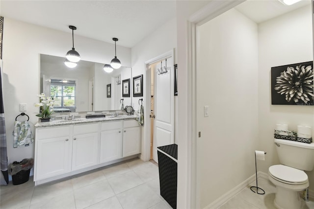 full bathroom with tile patterned floors, toilet, a sink, double vanity, and baseboards