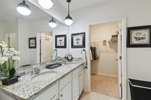 full bathroom featuring double vanity, tile patterned flooring, a walk in closet, and a sink