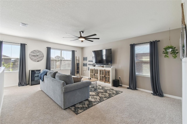 living area featuring plenty of natural light, carpet flooring, visible vents, and ceiling fan