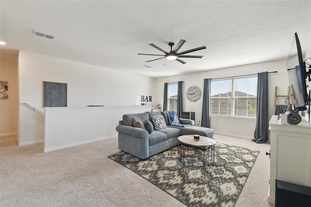 living area with a ceiling fan, baseboards, visible vents, a textured ceiling, and light carpet