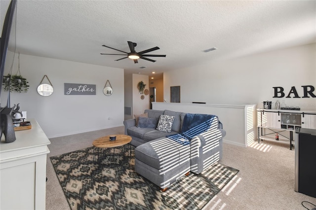 carpeted living area featuring a ceiling fan, baseboards, and a textured ceiling