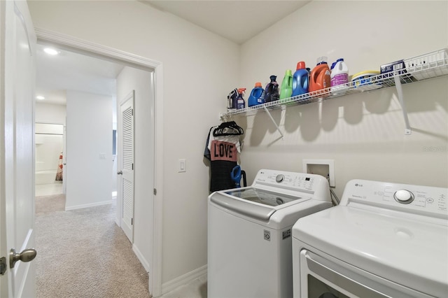 clothes washing area featuring laundry area, baseboards, independent washer and dryer, and light carpet