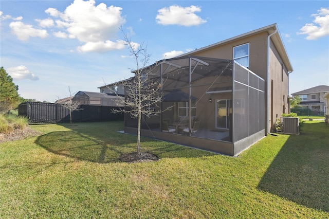 rear view of property featuring fence, central air condition unit, a lawn, glass enclosure, and stucco siding