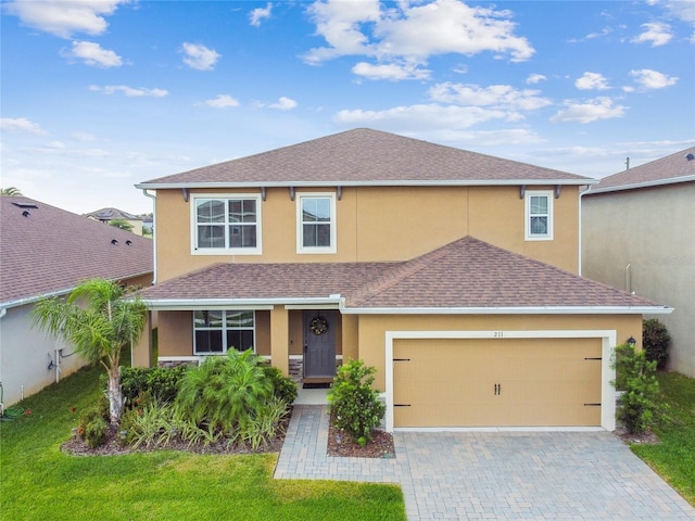 view of front of home featuring a shingled roof, stucco siding, driveway, and a front lawn