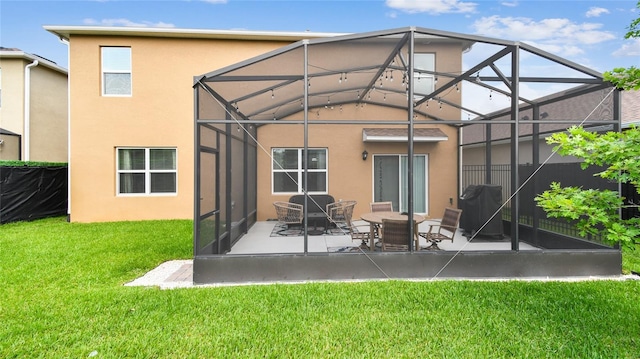 back of house featuring a lawn, glass enclosure, stucco siding, and a patio area