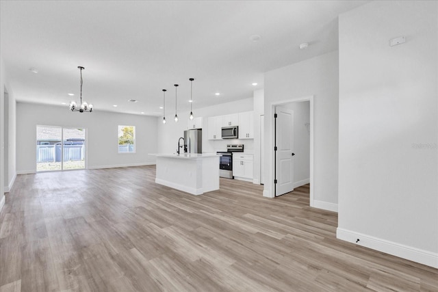 unfurnished living room with light wood-type flooring, a sink, recessed lighting, an inviting chandelier, and baseboards