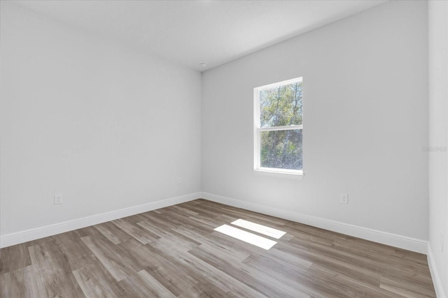 spare room featuring baseboards and wood finished floors