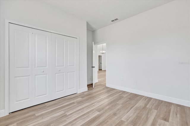 unfurnished bedroom featuring visible vents, baseboards, light wood-style floors, an inviting chandelier, and a closet