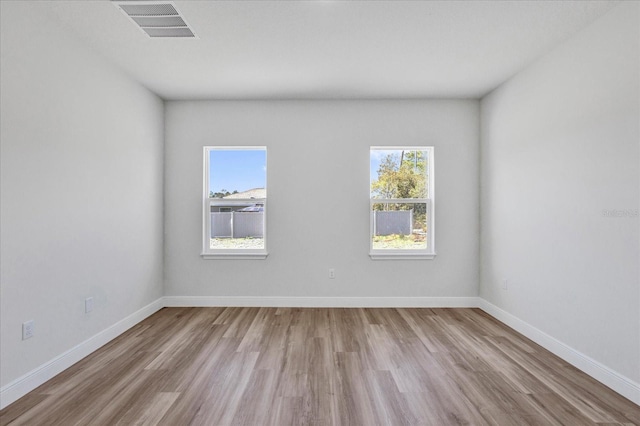 spare room with visible vents, baseboards, and wood finished floors