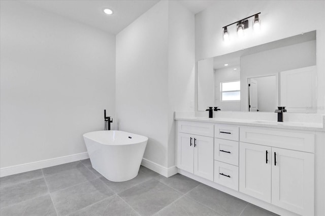 bathroom with tile patterned floors, a freestanding tub, a sink, double vanity, and baseboards