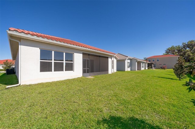 2400 Symphony Cir, Saint Cloud, FL 34771 - back of house featuring a yard, stucco siding, a tiled roof, and a sunroom