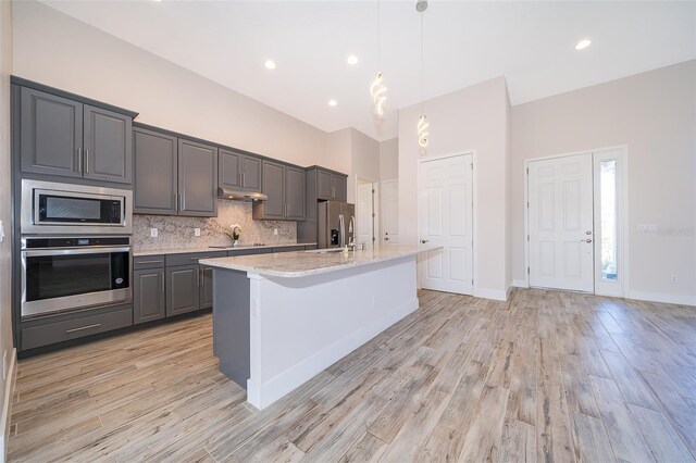 2400 Symphony Cir, Saint Cloud, FL 34771 - kitchen featuring tasteful backsplash, gray cabinets, an island with sink, light wood-style floors, and stainless steel appliances