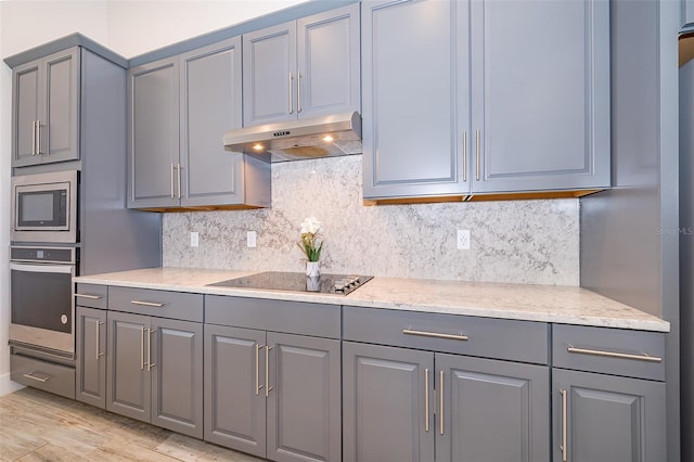 2400 Symphony Cir, Saint Cloud, FL 34771 - kitchen featuring tasteful backsplash, appliances with stainless steel finishes, gray cabinetry, and under cabinet range hood