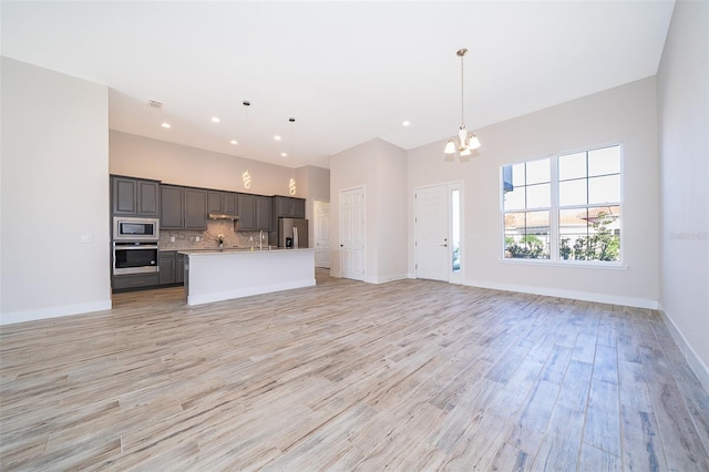 2400 Symphony Cir, Saint Cloud, FL 34771 - unfurnished living room with light wood finished floors, a notable chandelier, baseboards, and recessed lighting