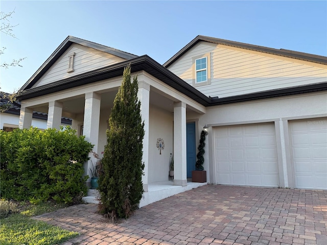 view of front of home featuring decorative driveway, a garage, and stucco siding