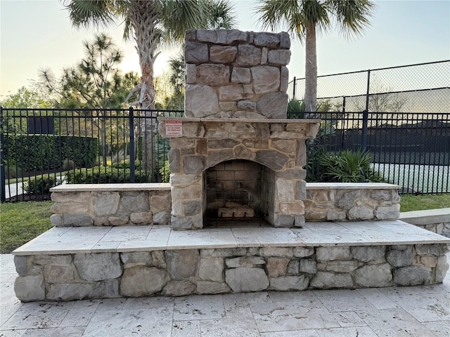 exterior details featuring fence and an outdoor stone fireplace