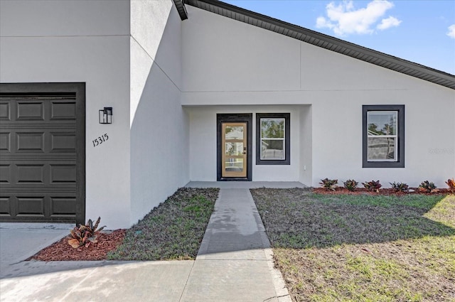 doorway to property featuring an attached garage and stucco siding