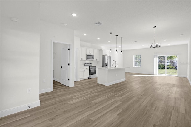 unfurnished living room featuring recessed lighting, light wood-type flooring, baseboards, and an inviting chandelier