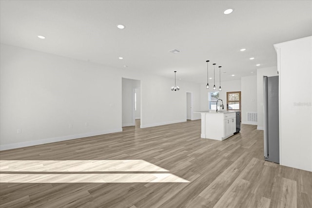 unfurnished living room featuring an inviting chandelier, recessed lighting, light wood-style floors, and visible vents