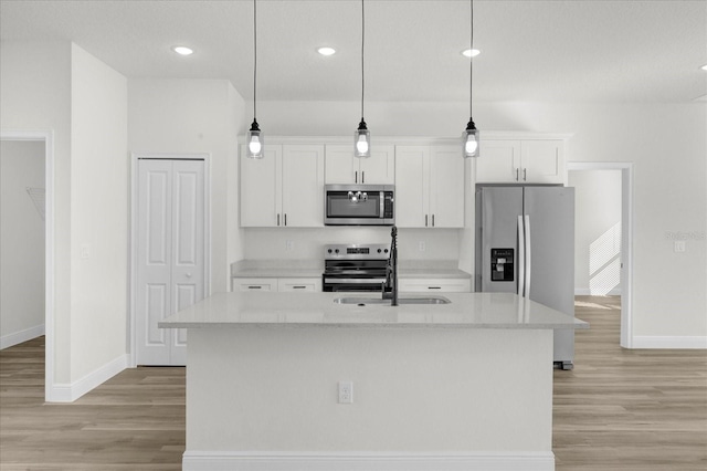 kitchen featuring a kitchen island with sink, light wood-type flooring, appliances with stainless steel finishes, and white cabinets