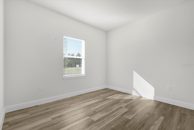 spare room featuring baseboards and wood finished floors