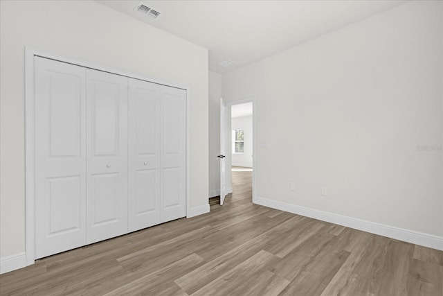 unfurnished bedroom with baseboards, visible vents, a closet, and light wood-type flooring