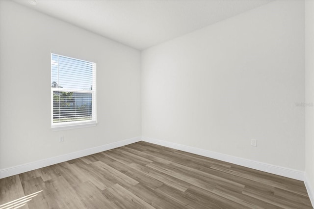 spare room with baseboards and wood finished floors